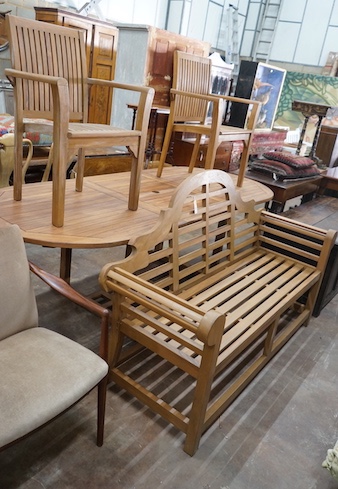 An extending teak garden table, length 140cm extended, width 100cm, height 75cm, a Lutyens style teak garden bench and two elbow chairs with waterproof covers